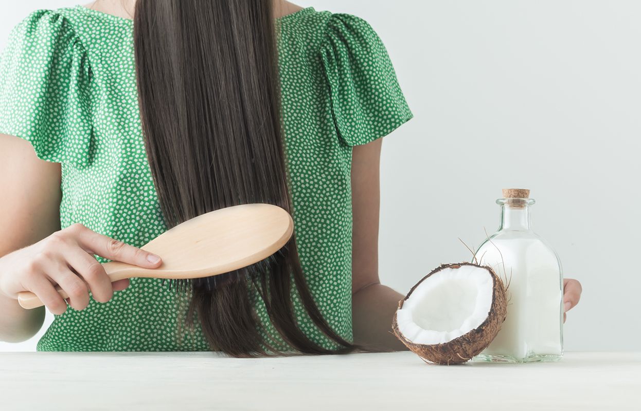 a woman with coconut based hair oil in her hand and flaunting gorgeous long hair