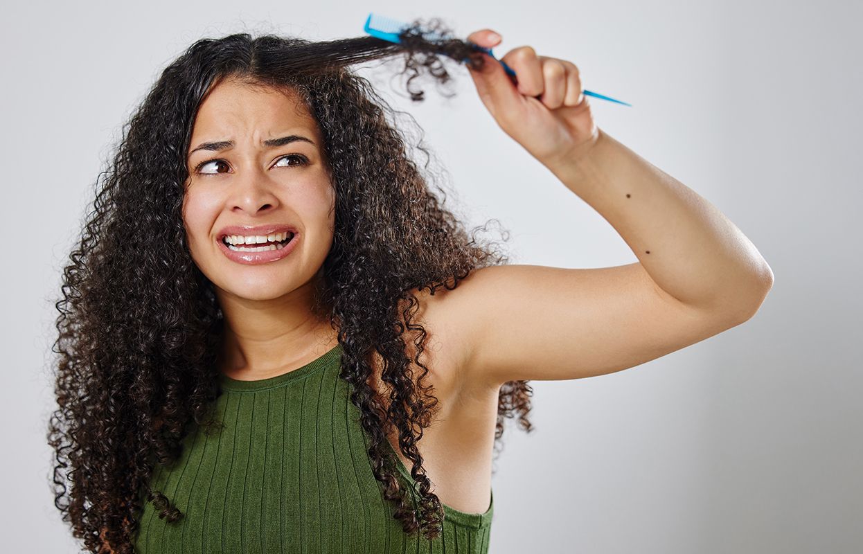 A woman with tangled curly hair with brush in hair
