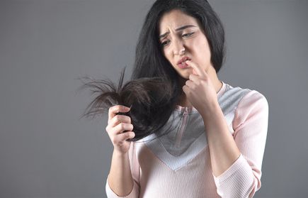 A woman thinking and seems frustrated with dry hair