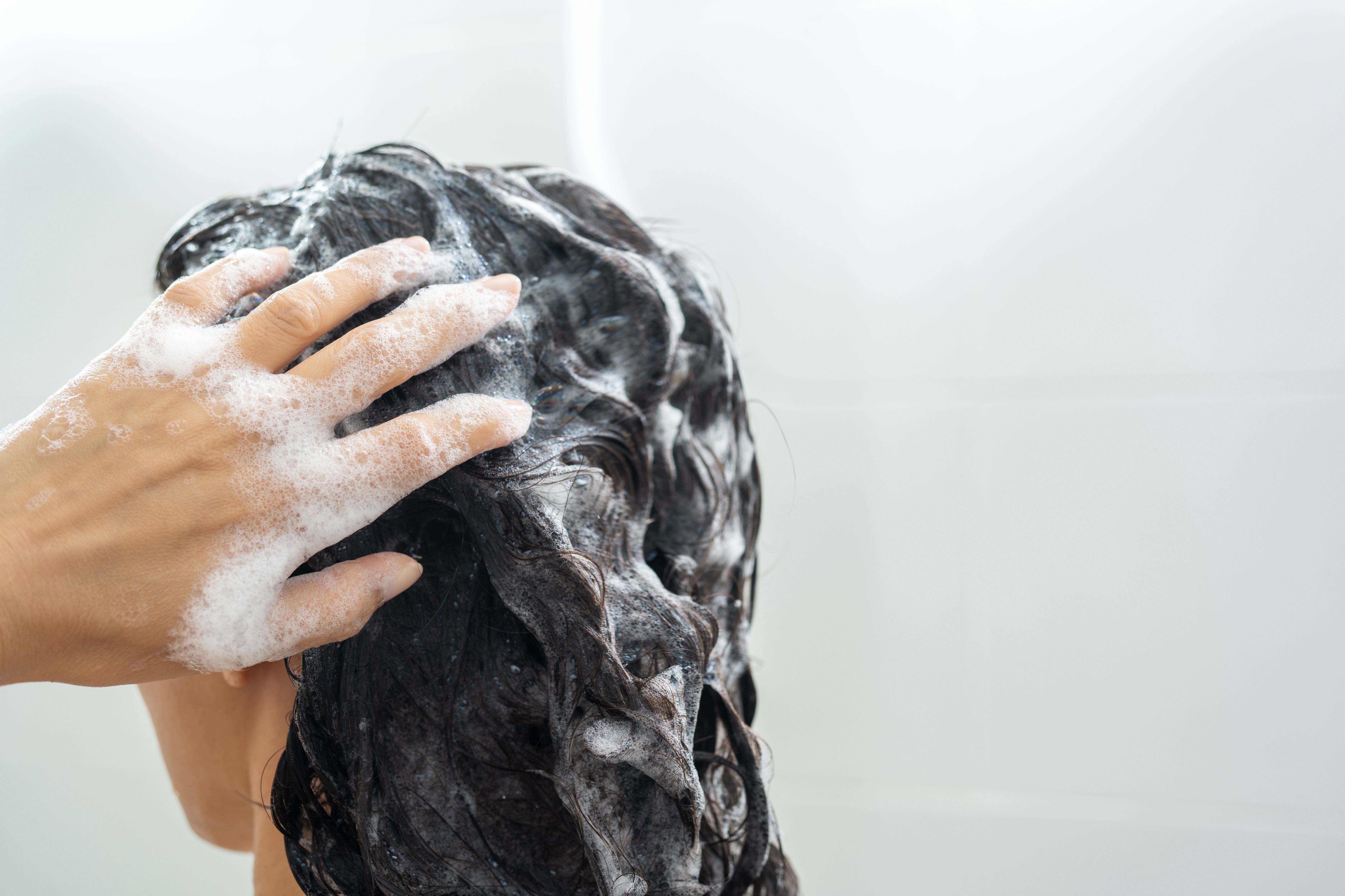 Girl applying shampoo to make her hair smell good