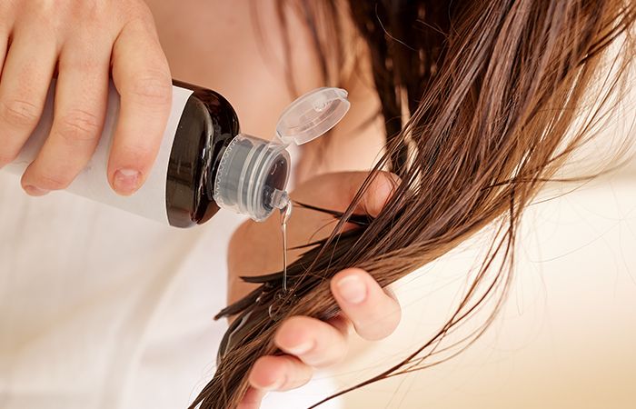 Girl applying oil to protect her hair